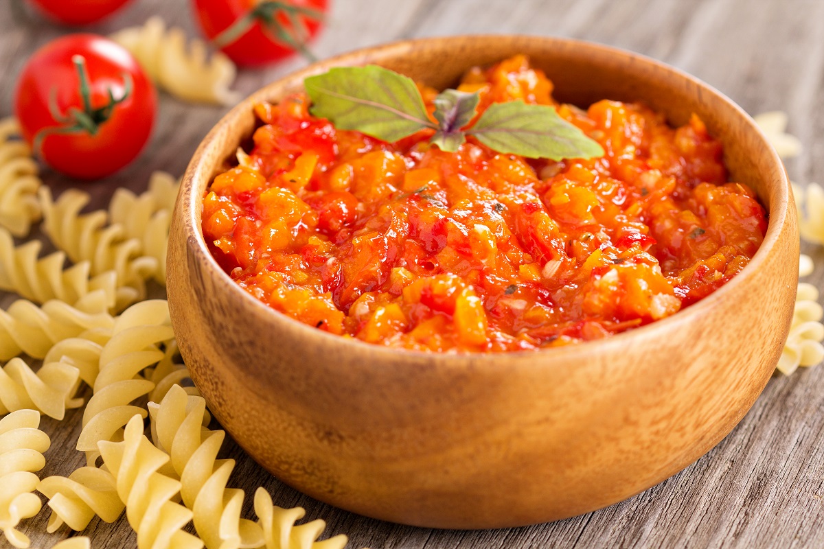 tomato-based Italian pasta sauce in a wooden bowl, surrounded by fusilli pasta