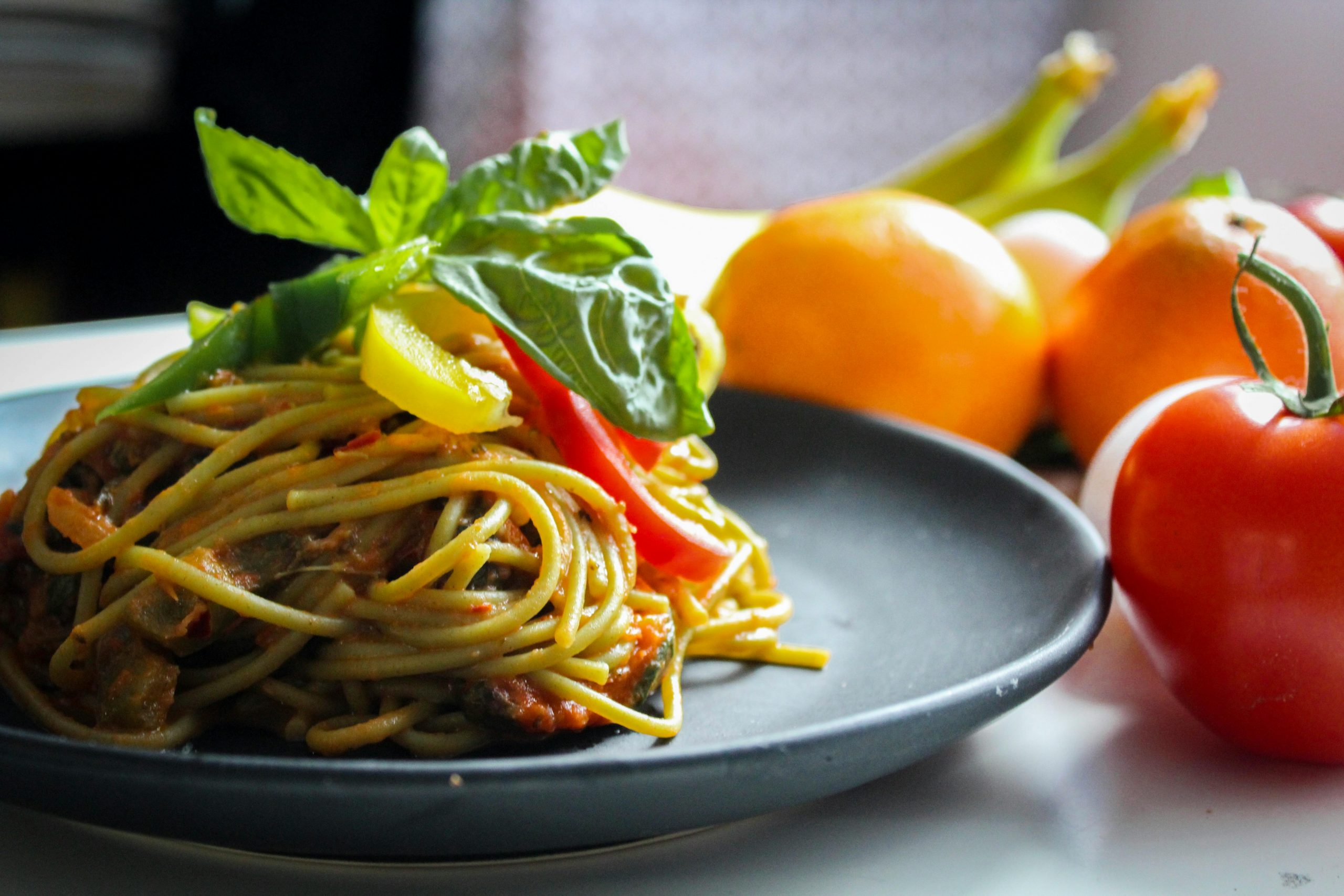 healthy Italian pasta on a blue plate, with fresh tomatoes next to it